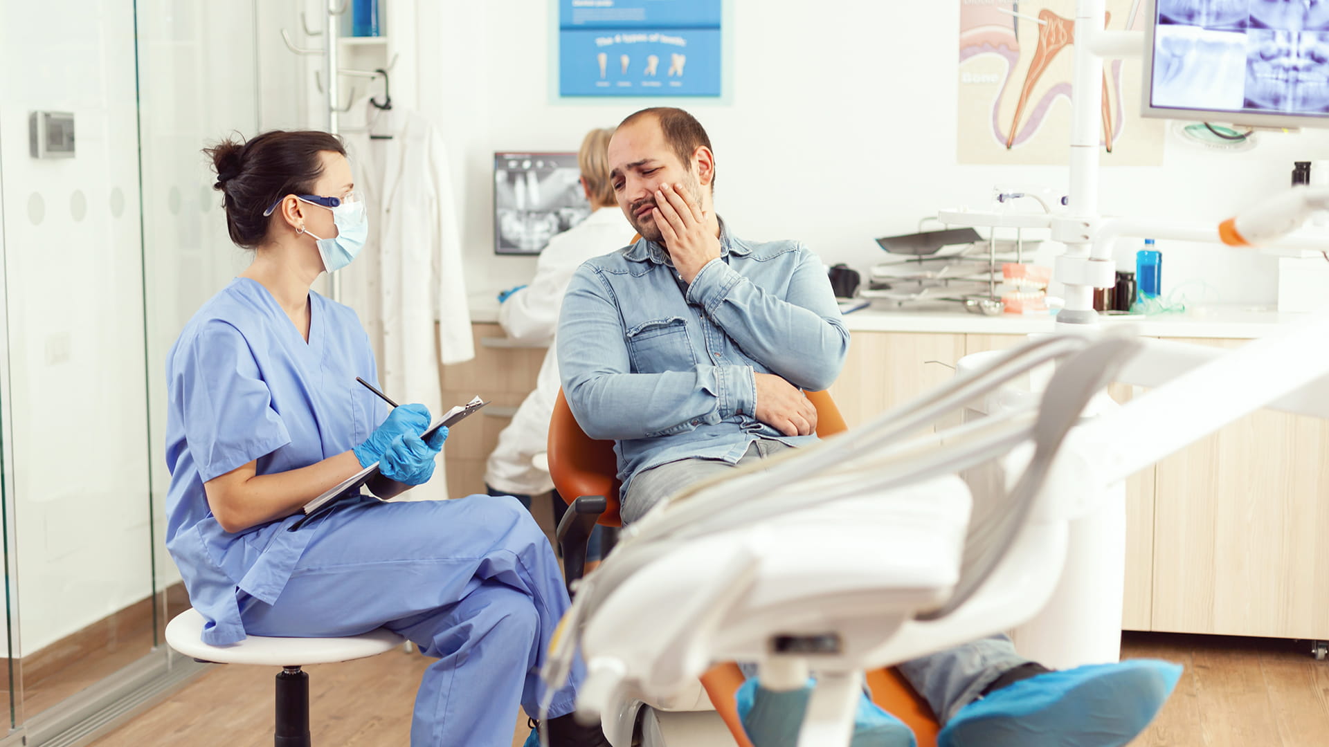 This image shows the consultation process in a reputable dental clinic made during an emergency dental visit. The man is shown with a pained expression, indicating an urgent dental issue.
